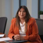 a woman in an orange blazer looking at the camera