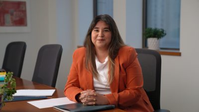 a woman in an orange blazer looking at the camera
